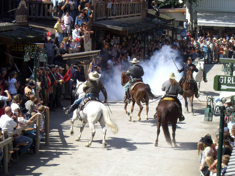 Eine Gruppe reitet auf Pferden durch eine Straße in Pullman City Westernstadt im Bayerischen Wald.