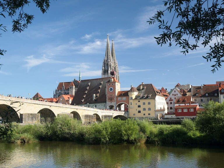 Eine malerische Steinbrücke überspannt den Fluss vor der Altstadt von Regensburg.
